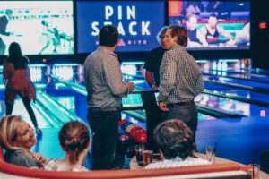 Image of young co-workers talking in between bowling on the lanes.