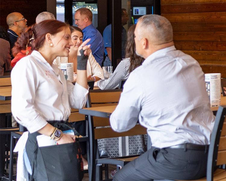 Image of a Pinstack server enjoying conversation with a guest on the climate-controlled patio.