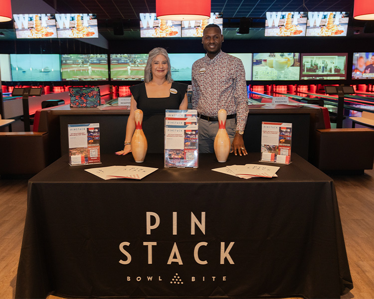 Image of Pinstack Sales Managers standing by table with information on group events and parties.