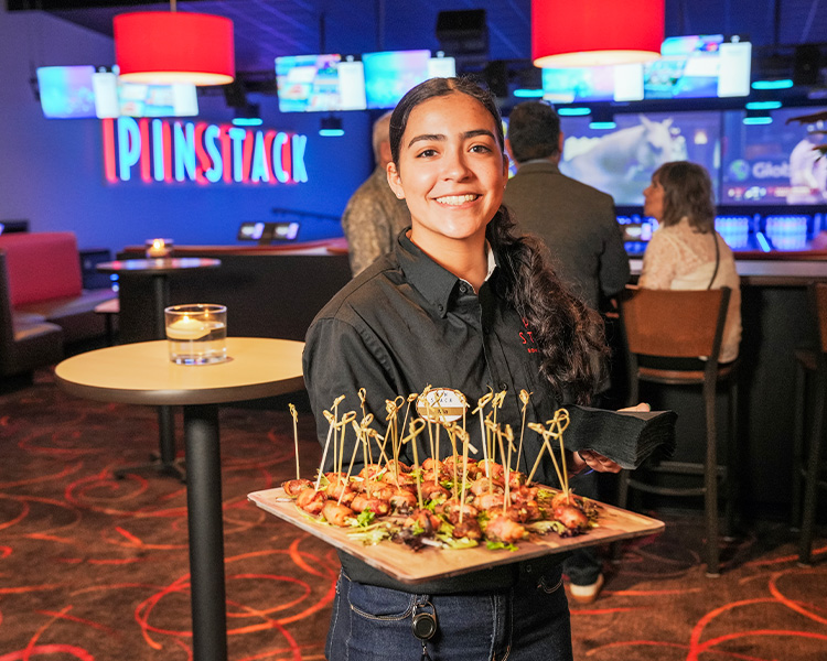 Image of a server holding a tray of bacon jalapeno wraps.