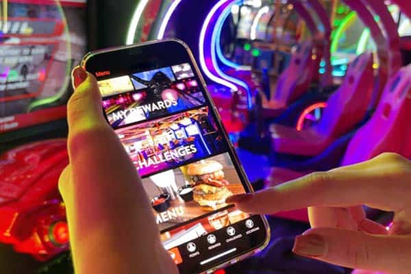 A photo of a smartphone displaying the Pinstack Perks app while a finger scrolls through the options.