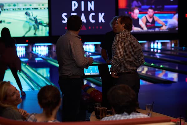A photo of a small group of young professionals at a team building event on the bowling lanes at Pinstack.