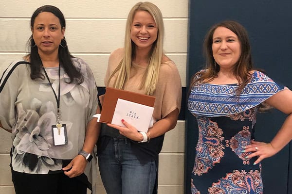 An image of a Teacher of the Month being presented with a special gift from Pinstack by the Las Colinas team.